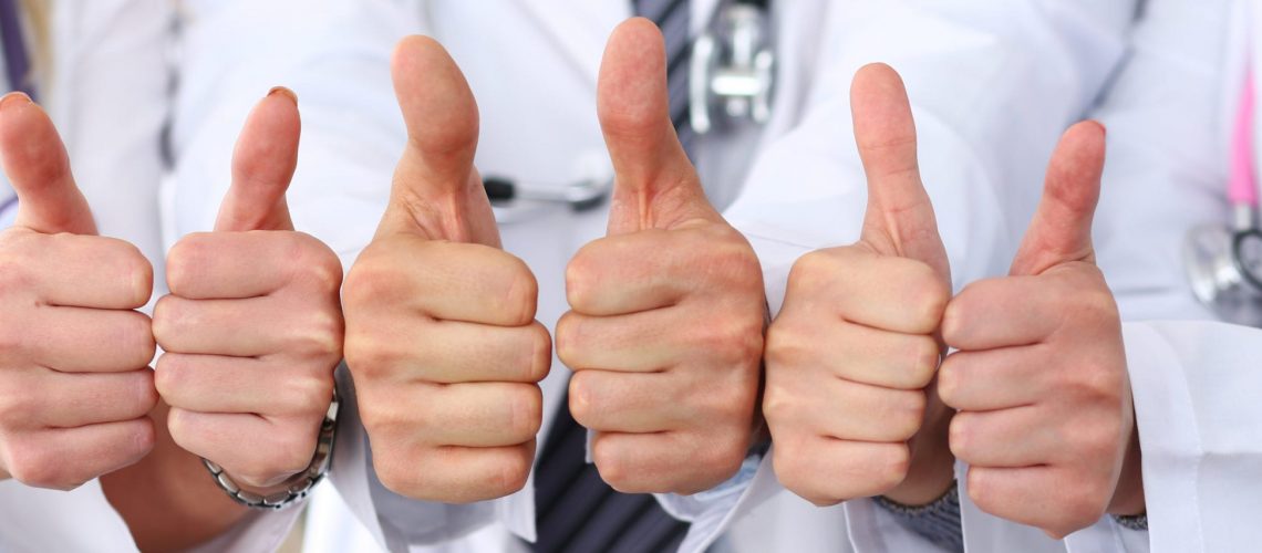 Three doctors show OK sign with thumb up in row.