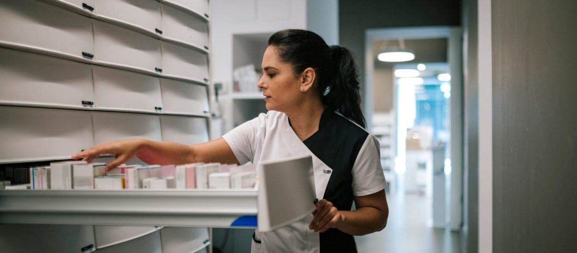 Pharmaceutical woman taking medication from drawers in a pharmacy
